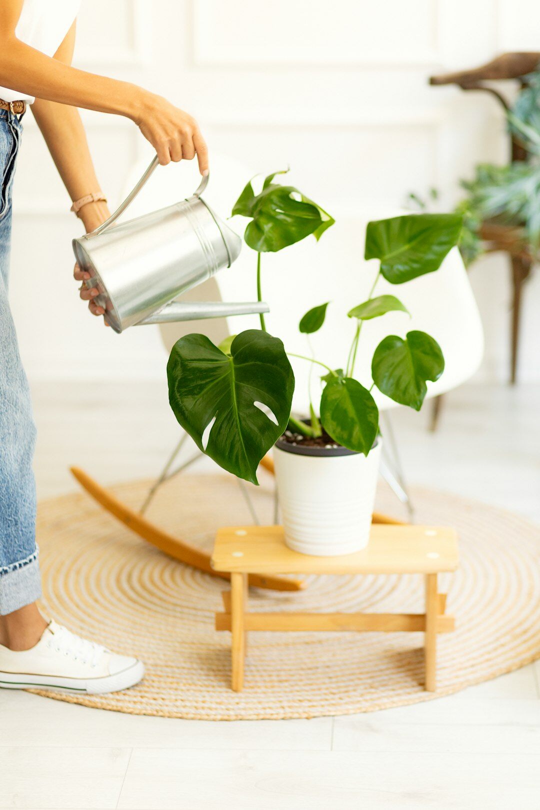 Hispanic woman watering a potted plant with a small metal watering can